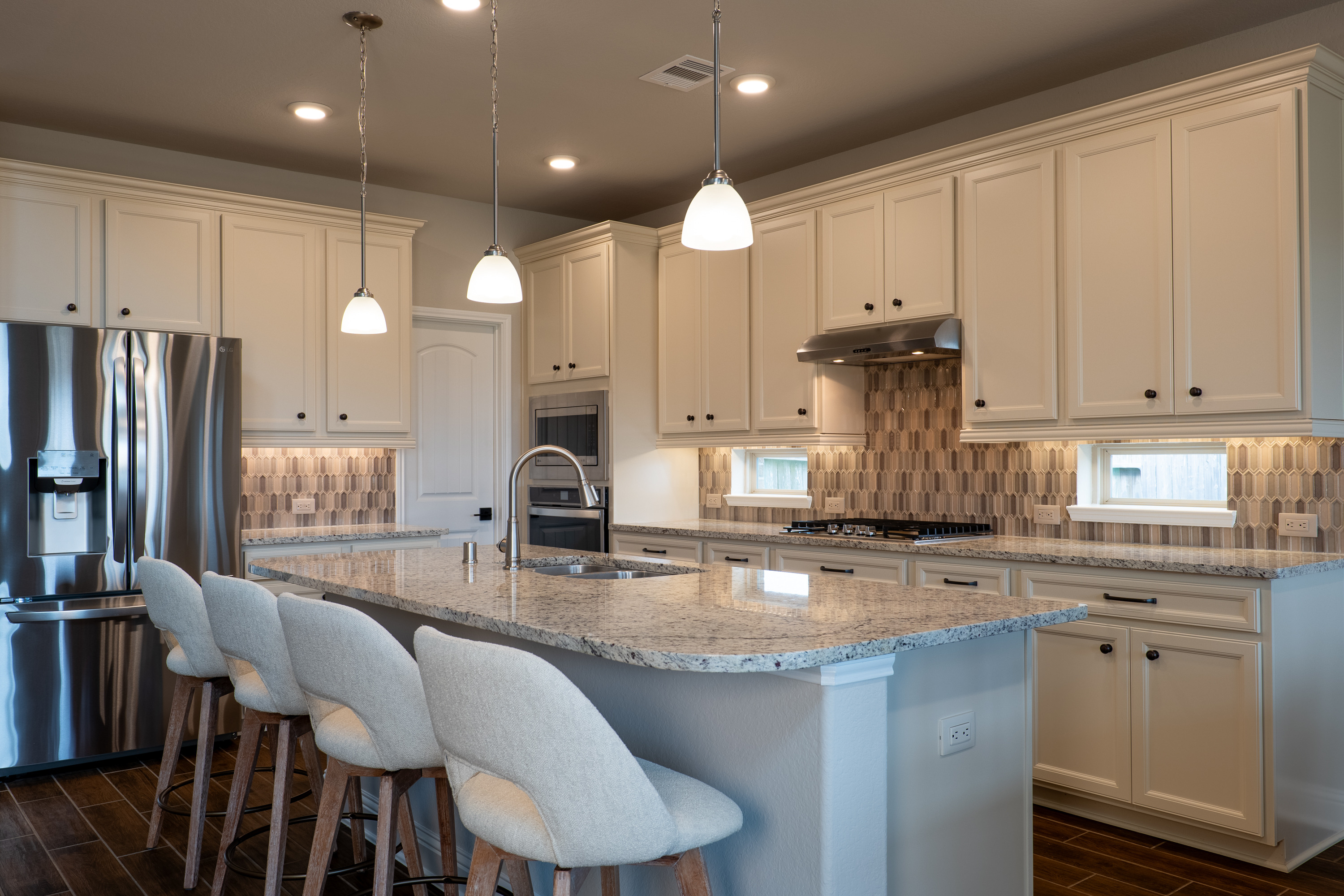 Dallas White granite, vertical-picket mosaic full backsplash, under-cabinet lighting, and a built-in wall oven. Delta pull-down faucet new in 2025.