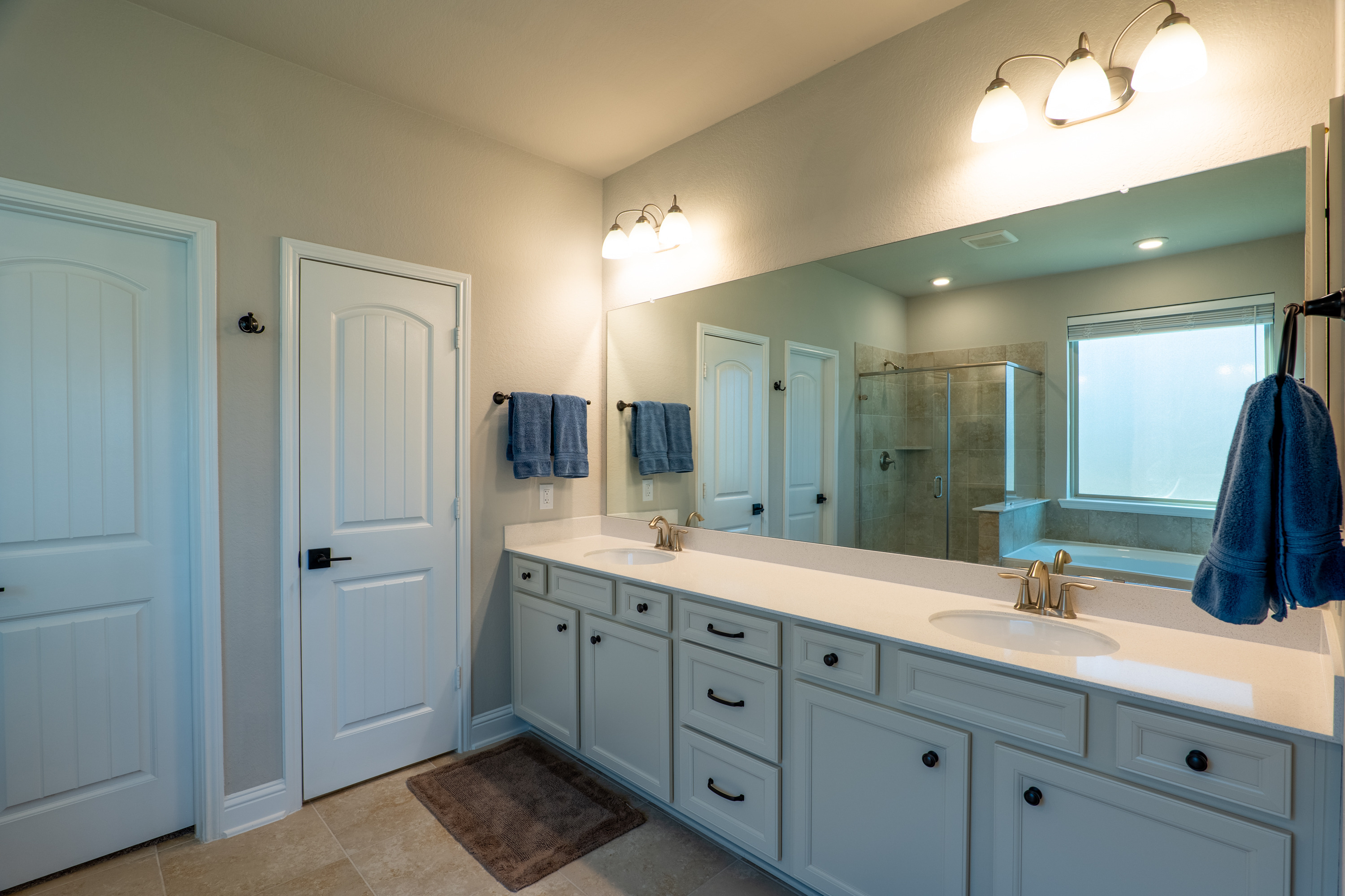 Primary bathroom with double vanity, lots of storage. Doors lead to the toilet room and walk-in closet.