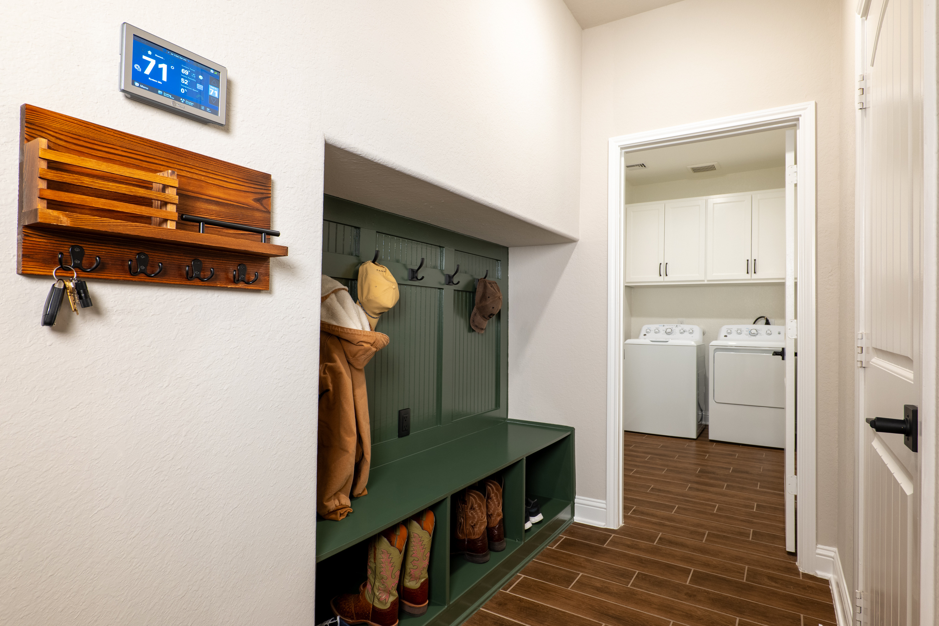 Built-in valet at the garage entry—hooks, bench, cubbies, and power. Trane XL1050 smart thermostat.
