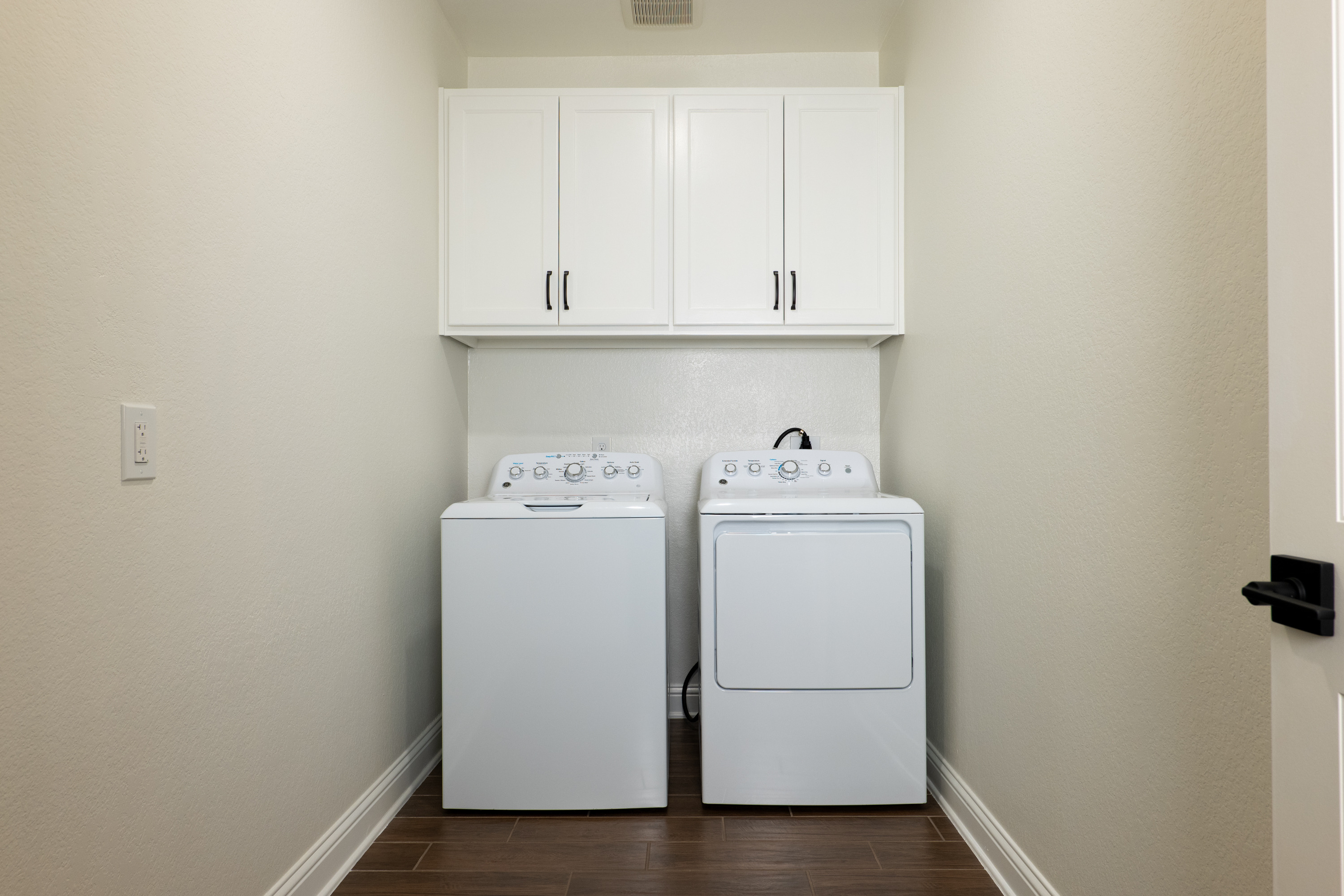 Laundry room with custom-built upper cabinets. Natural gas and electric dryer connections.