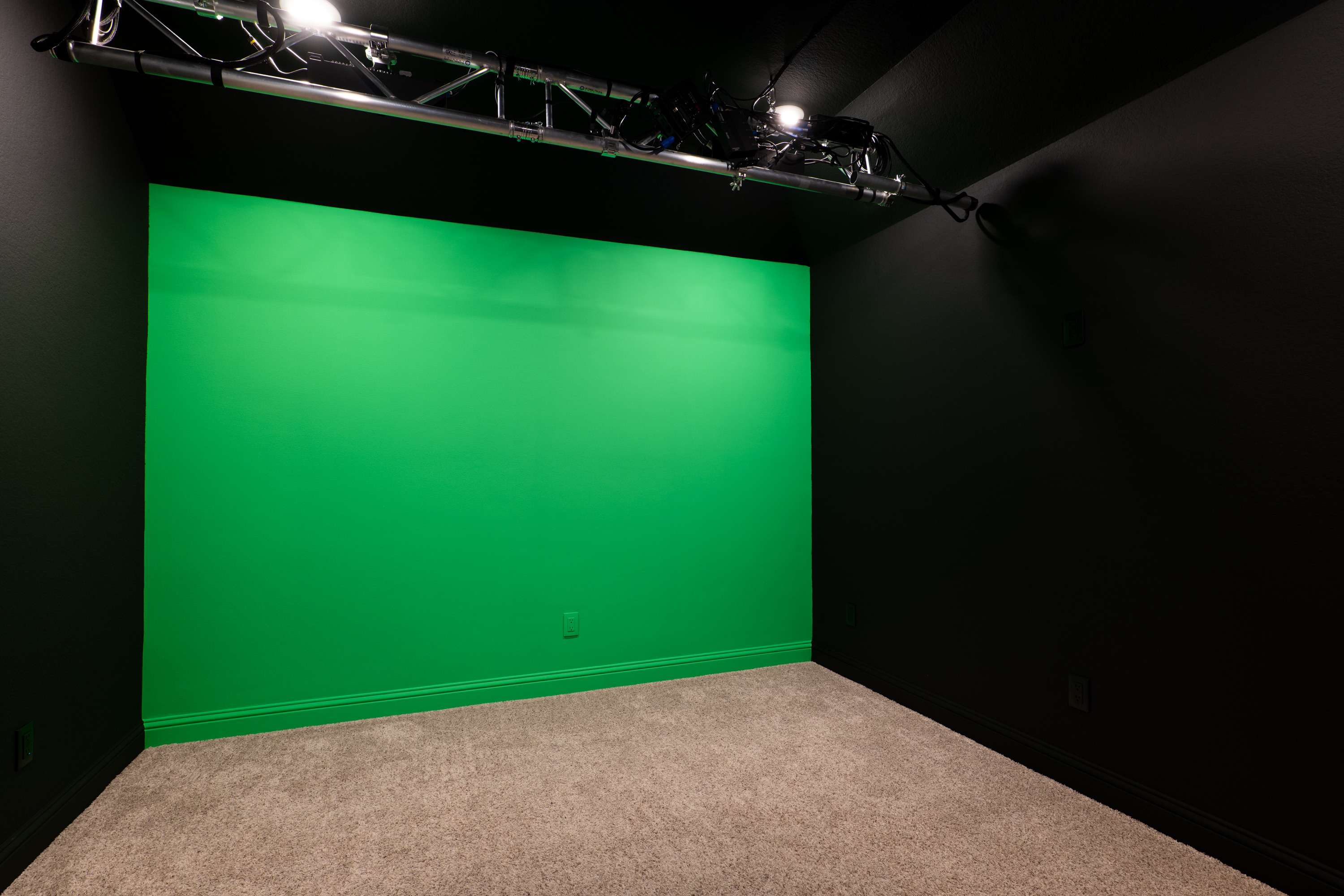 Windowless media room, blacked out and prewired for surround sound, currently set up as a video studio with a chroma-green wall.