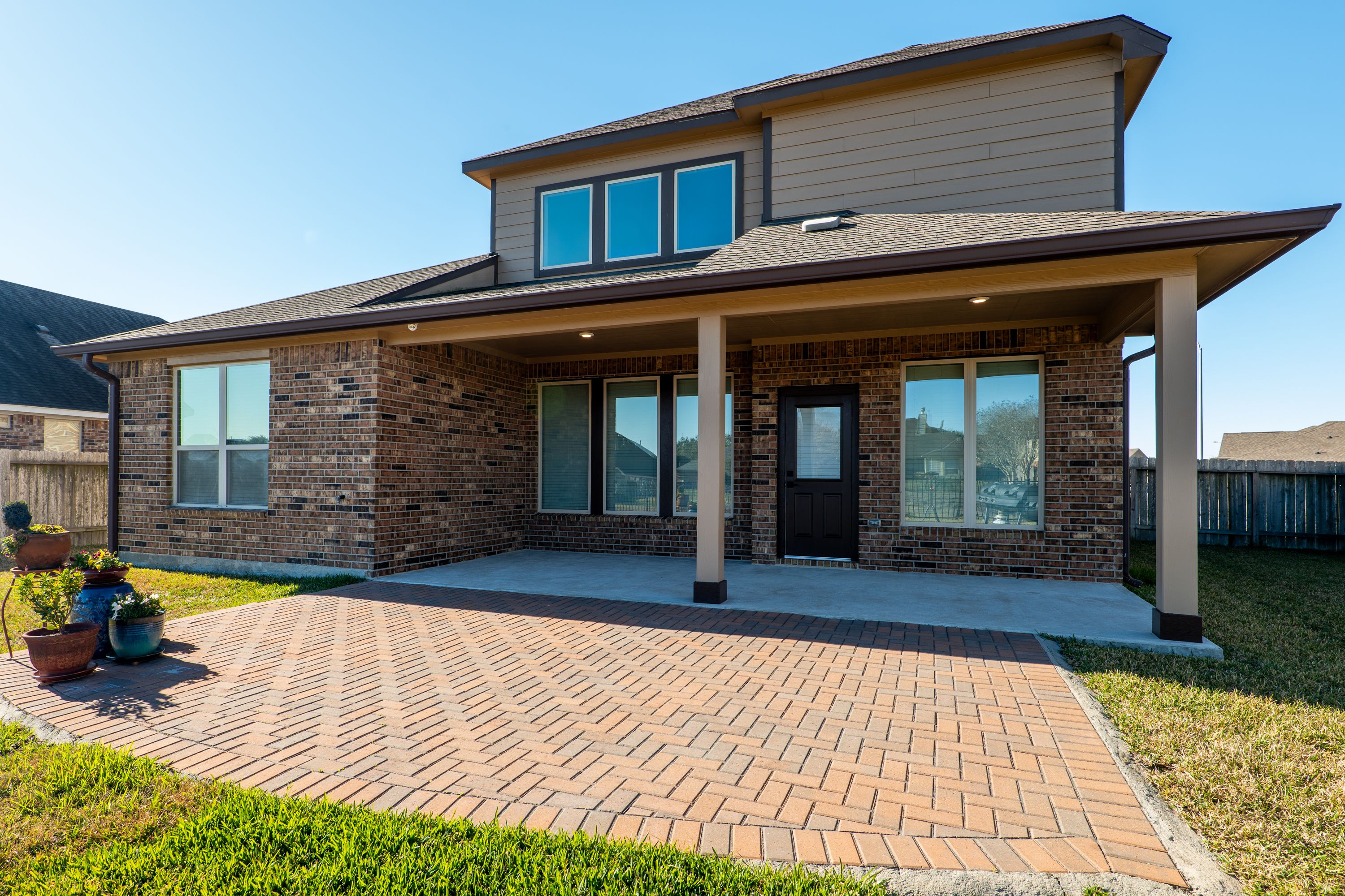 Large back porch opens onto a 21′-wide brick paver patio.