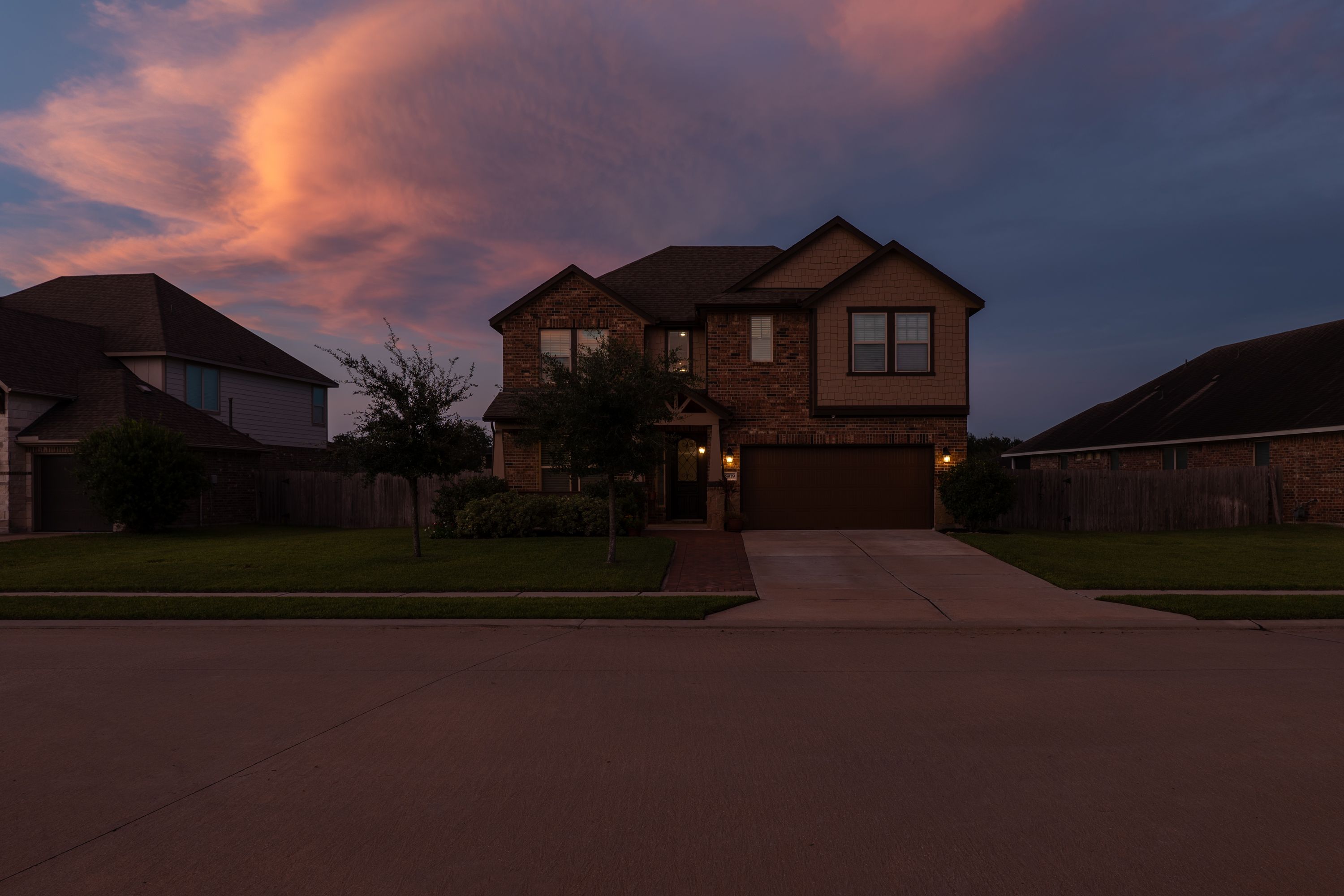 Front of the house at dusk with the porch lights on.