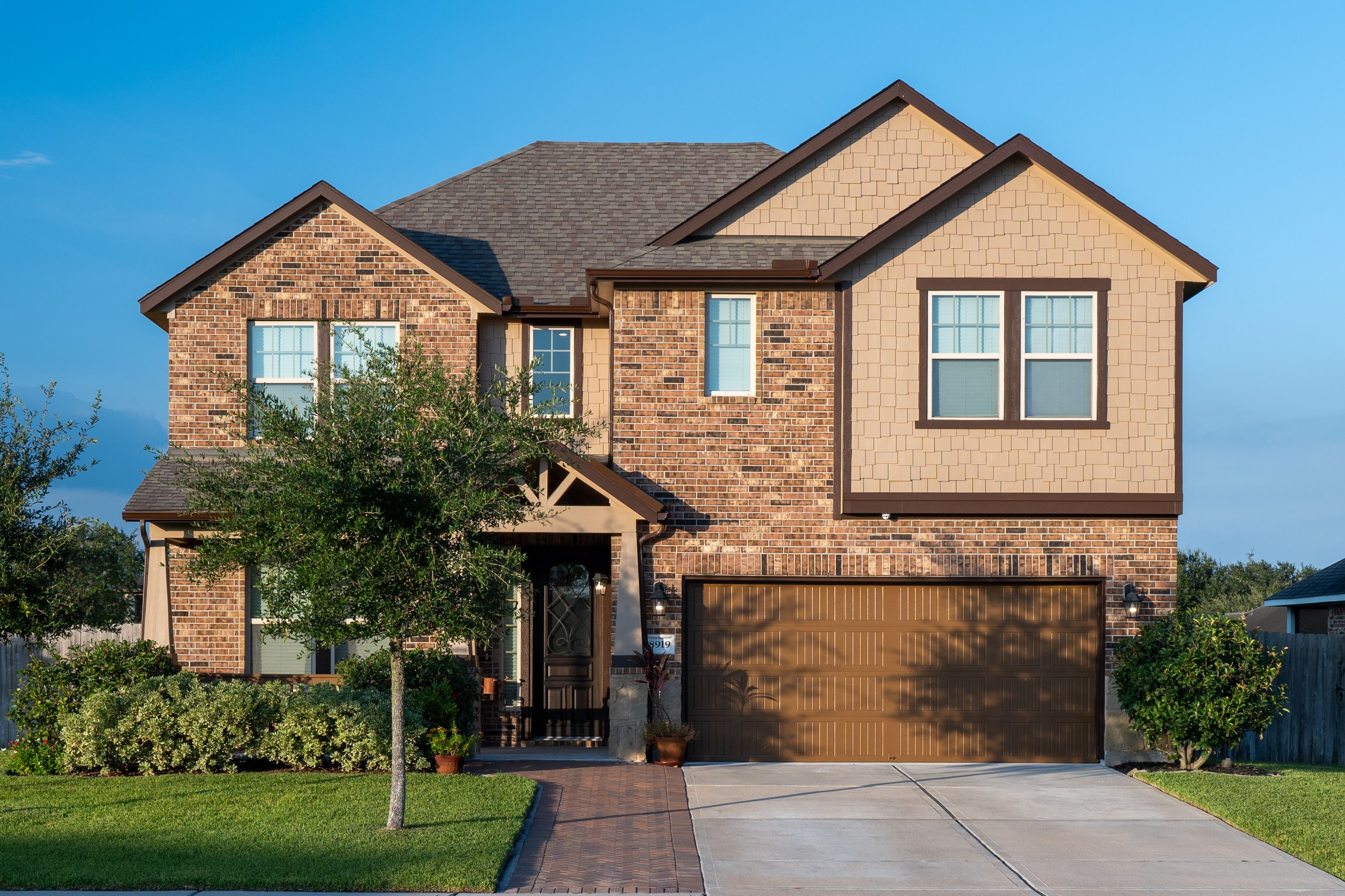 Craftsman brick-and-shake two-story with chocolate trim and a herringbone brick walk. 4 bed, 3.5 bath, 2,905 sq ft.